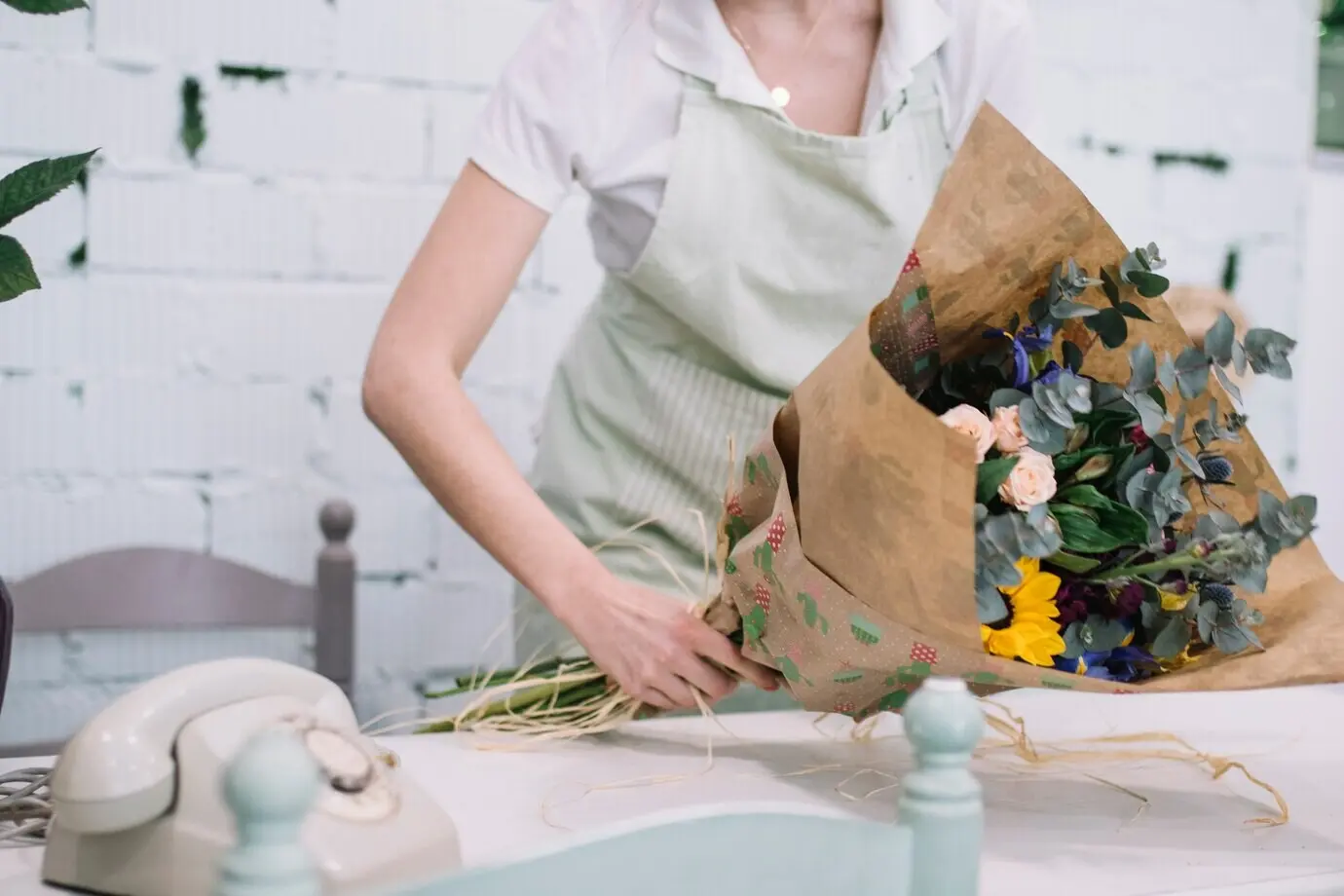 Mitarbeiter stellt im Geschäft einen Blumenstrauß zusammen.